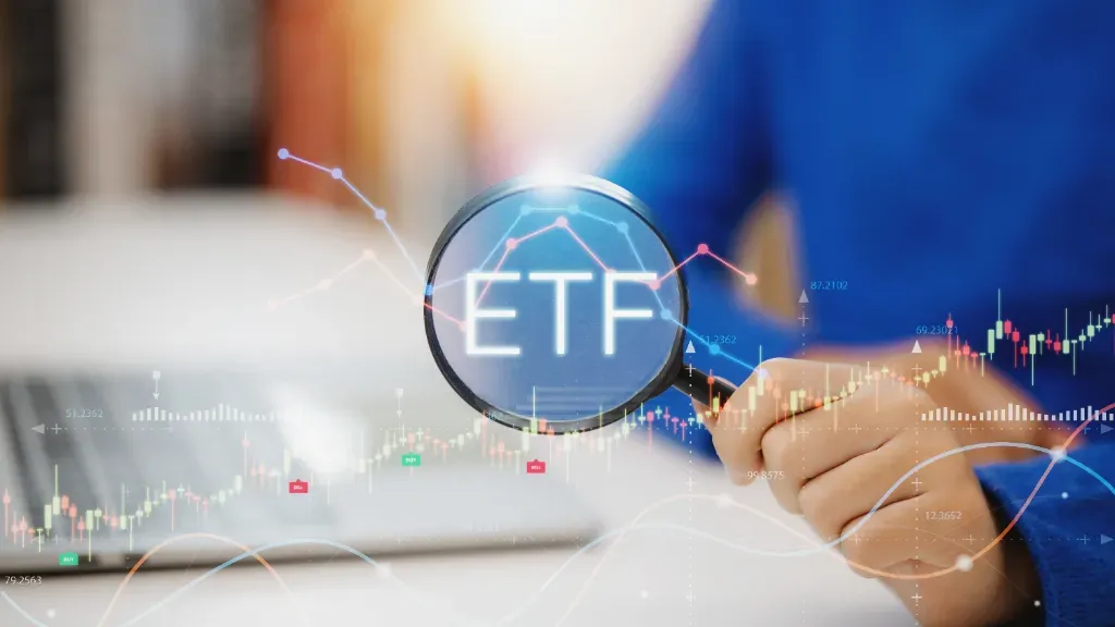 Mężczyzna trzyma lupę w dłoni skierowaną na ETF-y, aby dowiedzieć się, jak w nie inwestować